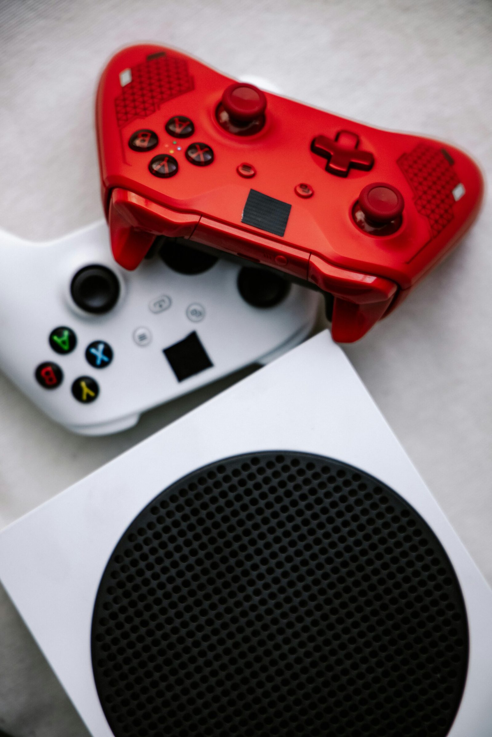 Home Vertical shot of vibrant red and white game controllers on a modern console.
